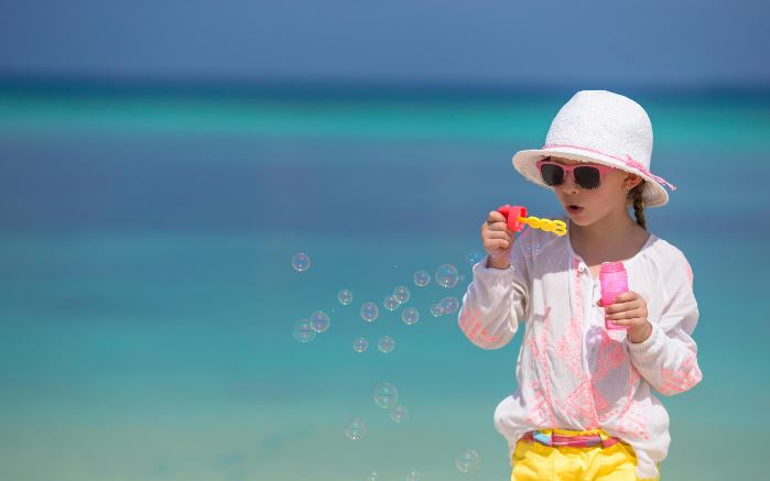 A girl blowing bubbles at the beach