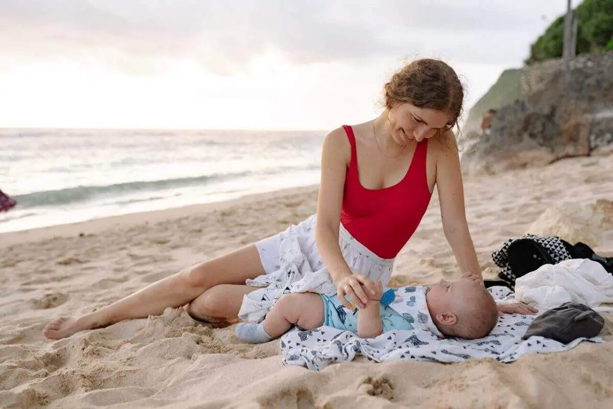 mother-taking-newborn-at-beach-smiling